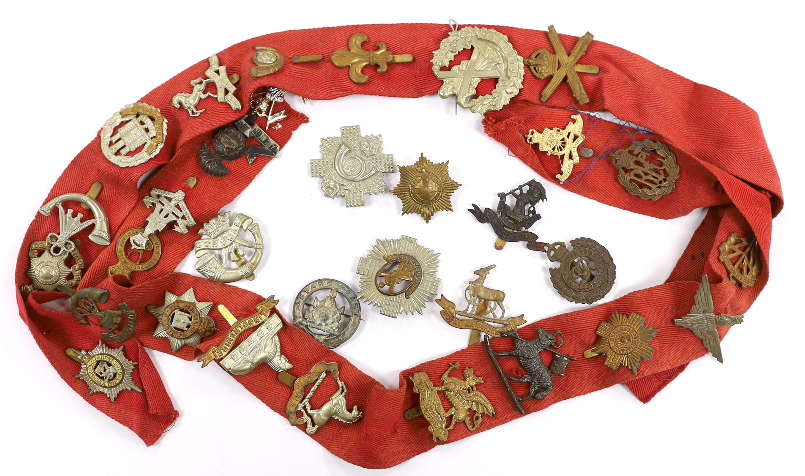 Thirty-two military cap badges, including; The Devonshire Reg., The Buffs, RFC, Royal Artillery, The Royal Sussex Reg. Royal Warwickshire Reg., Cornwall, etc.